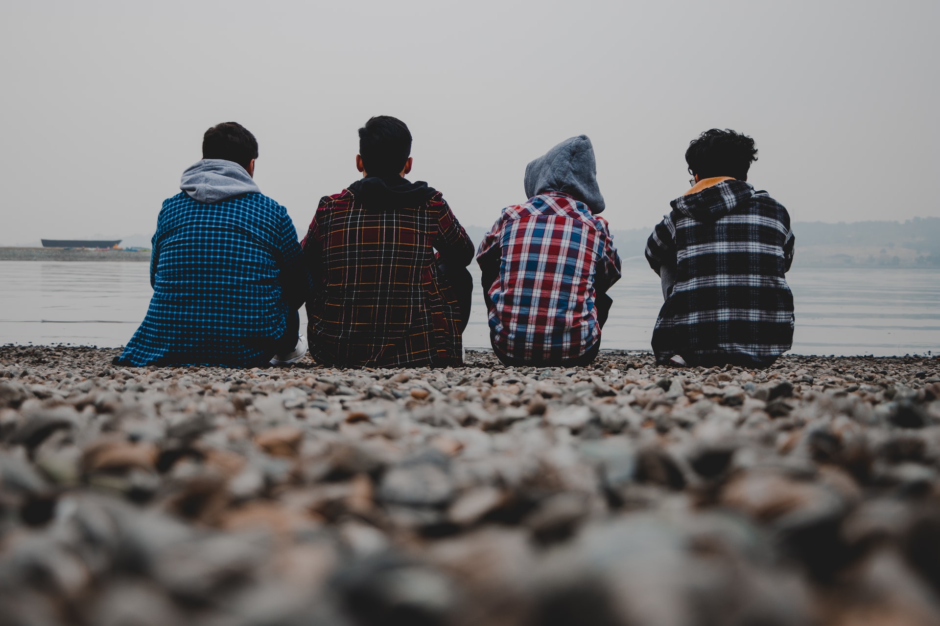 4名青少年坐在石滩上望海